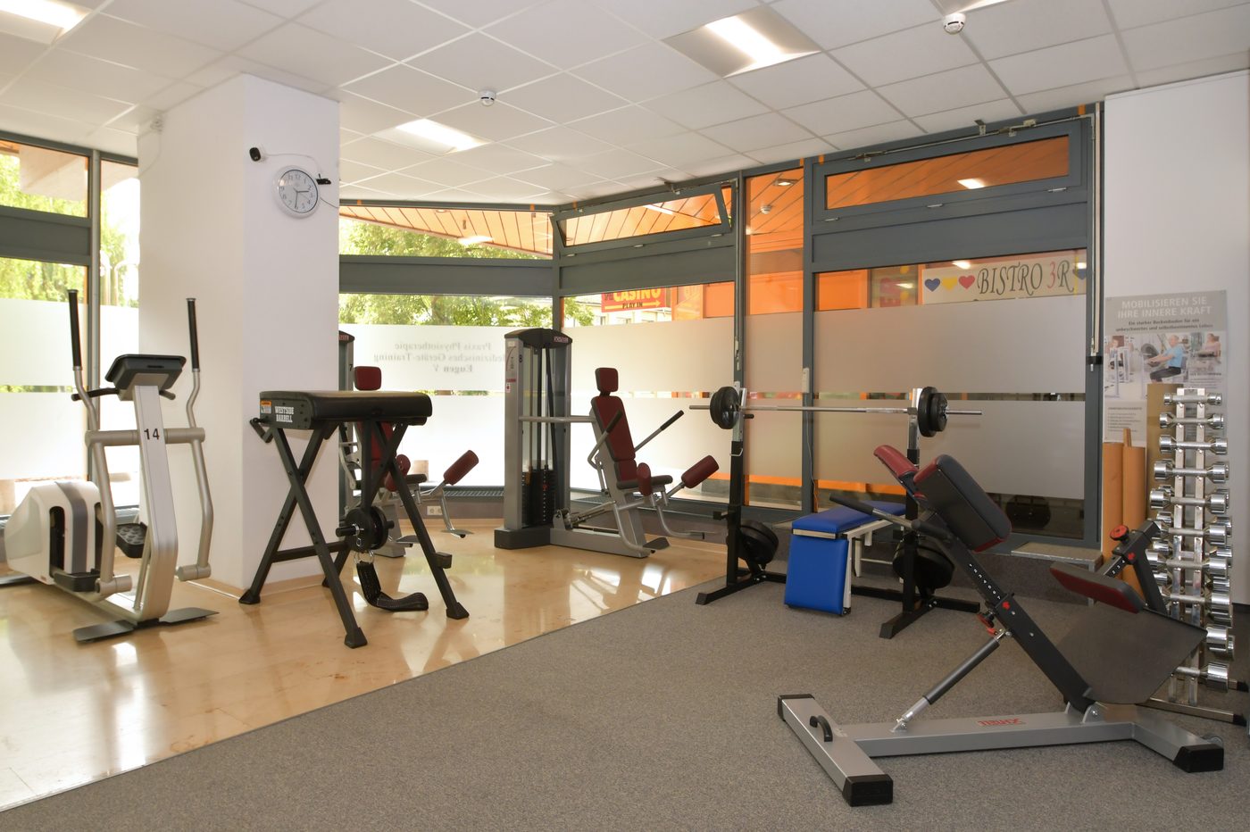 Heller Trainingsraum mit Fenstern, Bänken und Hanteln